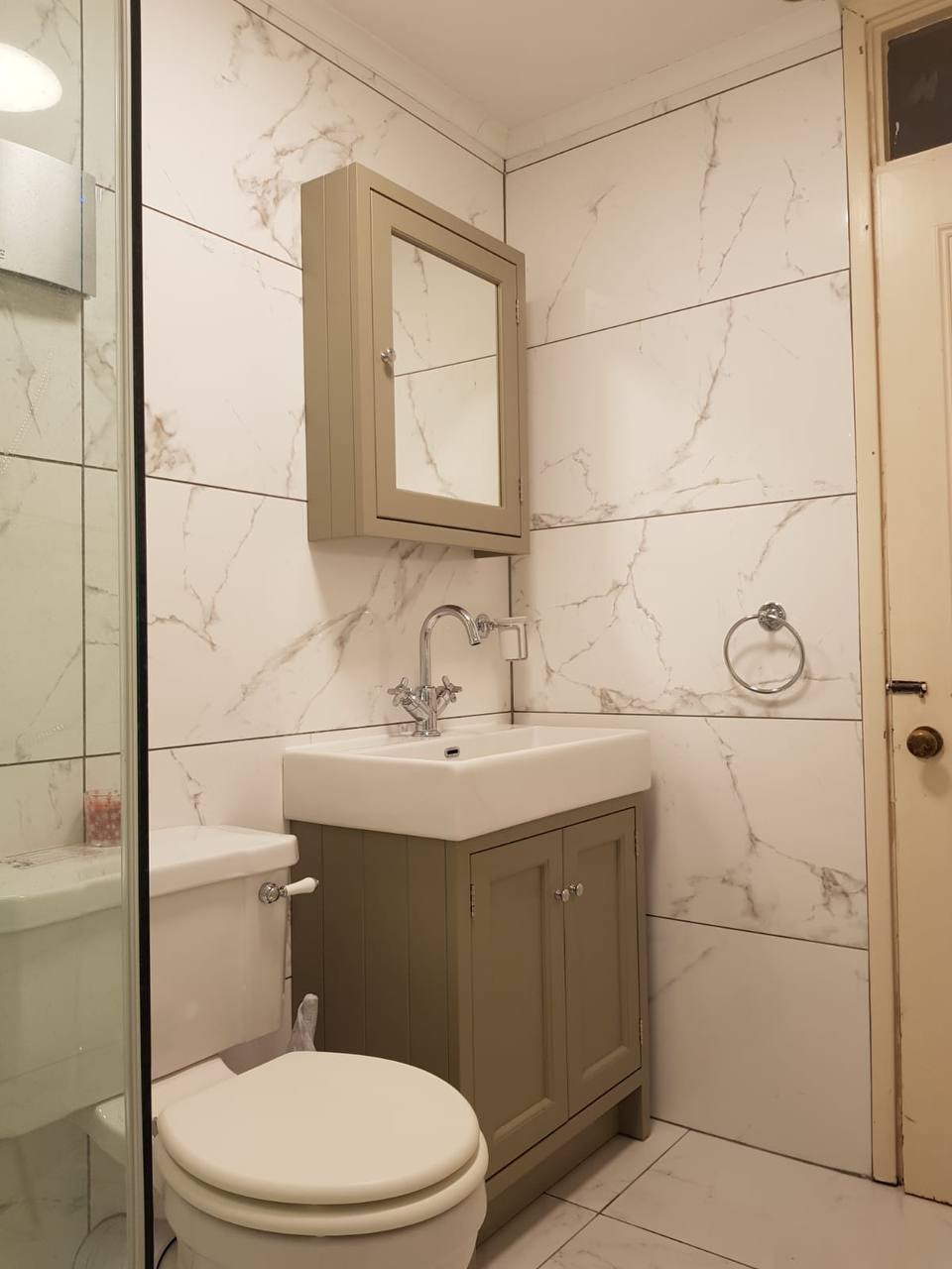 Completed bathroom with marble-effect wall tiling, vanity and shower — West London