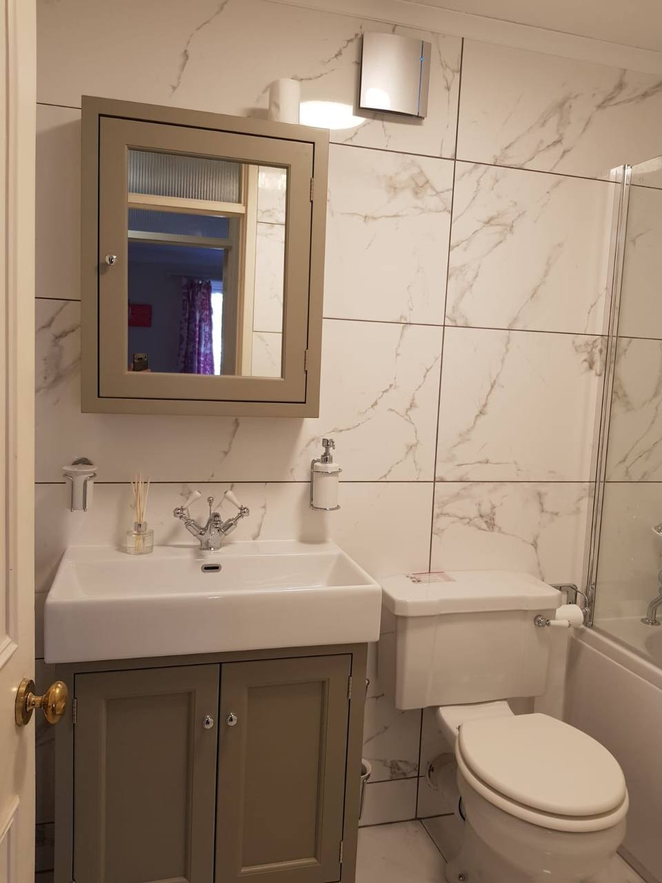 Completed bathroom with marble-effect wall tiling and bath — West London